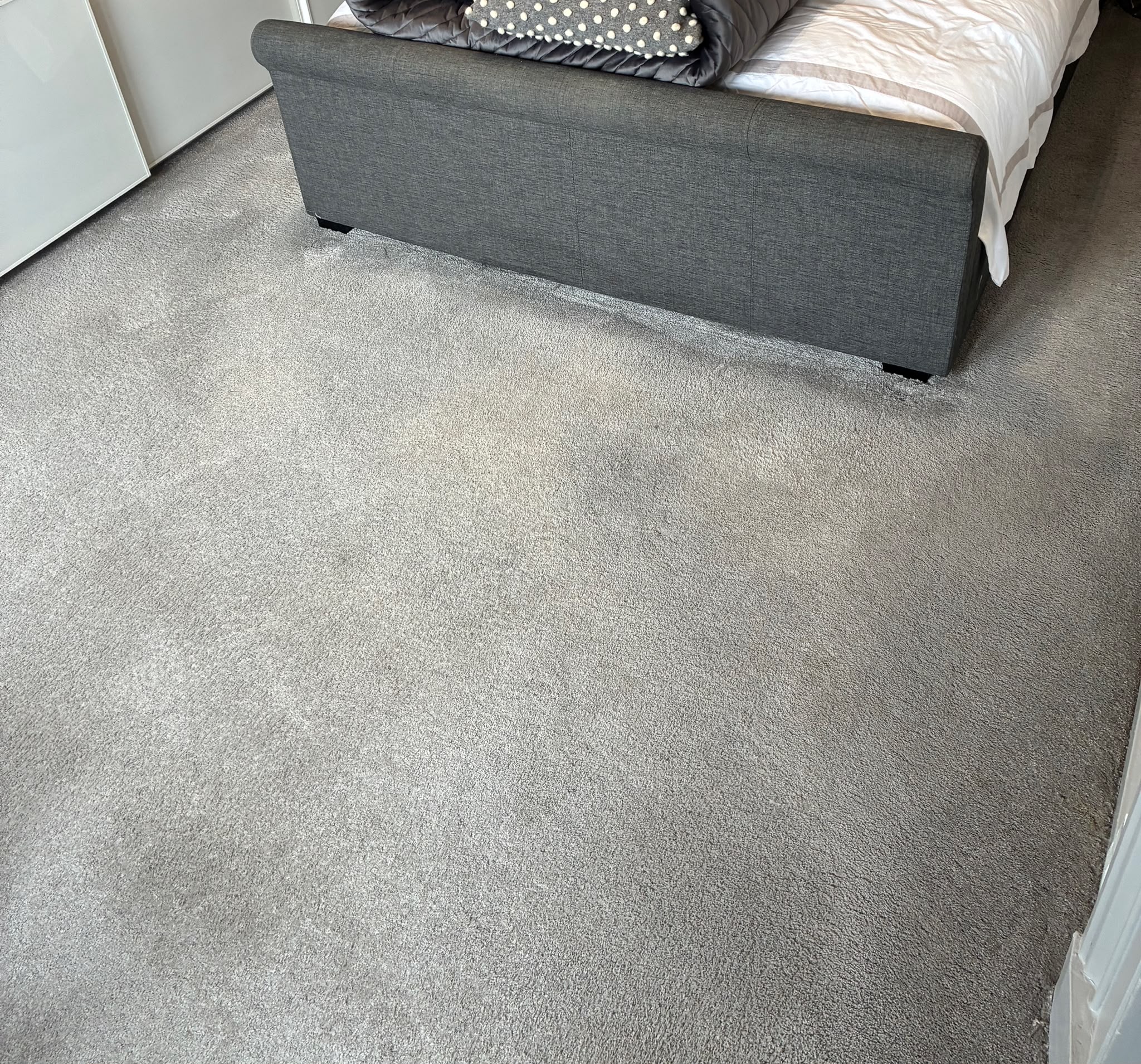 Grey carpet around a bed in a customer room photographed by MERIT